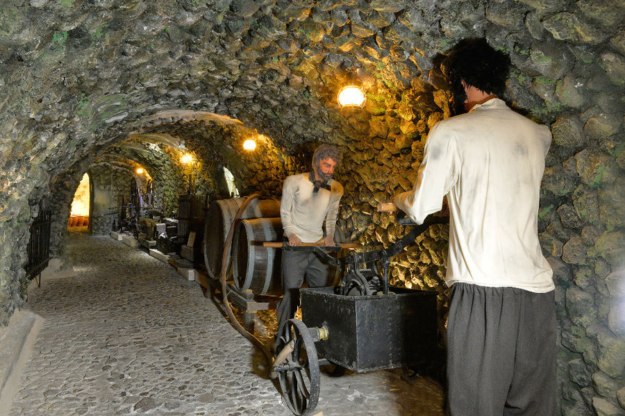 exhibit shows men turning grape press wheel 'Koutsoyannopoulos Wine Museum'